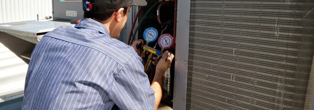 HVAC technician servicing a condenser unit in Walker